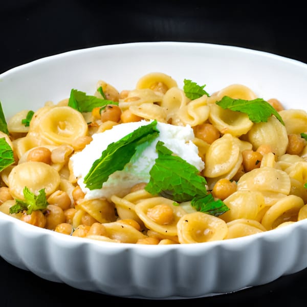 Orecchiette pasta with chickpeas, ricotta cheese, and fresh mint in a white bowl.