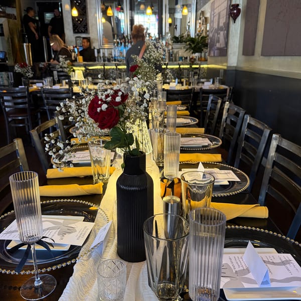 A long table set for a special event at The 808 Bistro, with red roses and baby's breath.