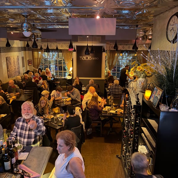 Diners enjoying meals at tables in the warmly lit, bustling interior of The 808 Bistro.