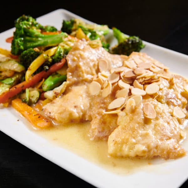 The 808 Bistro's chicken dish with sliced almonds, served with a side of broccoli and carrots.