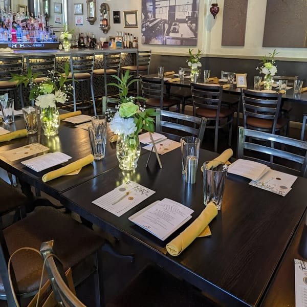 Set tables with menus, glasses, yellow napkins, and floral centerpieces in The 808 Bistro dining room.