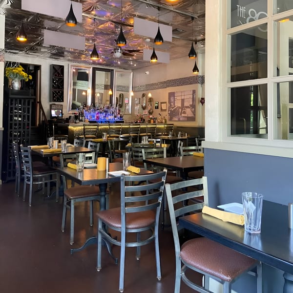 The 808 Bistro's dining room with tables, chairs, and a bar in the background.