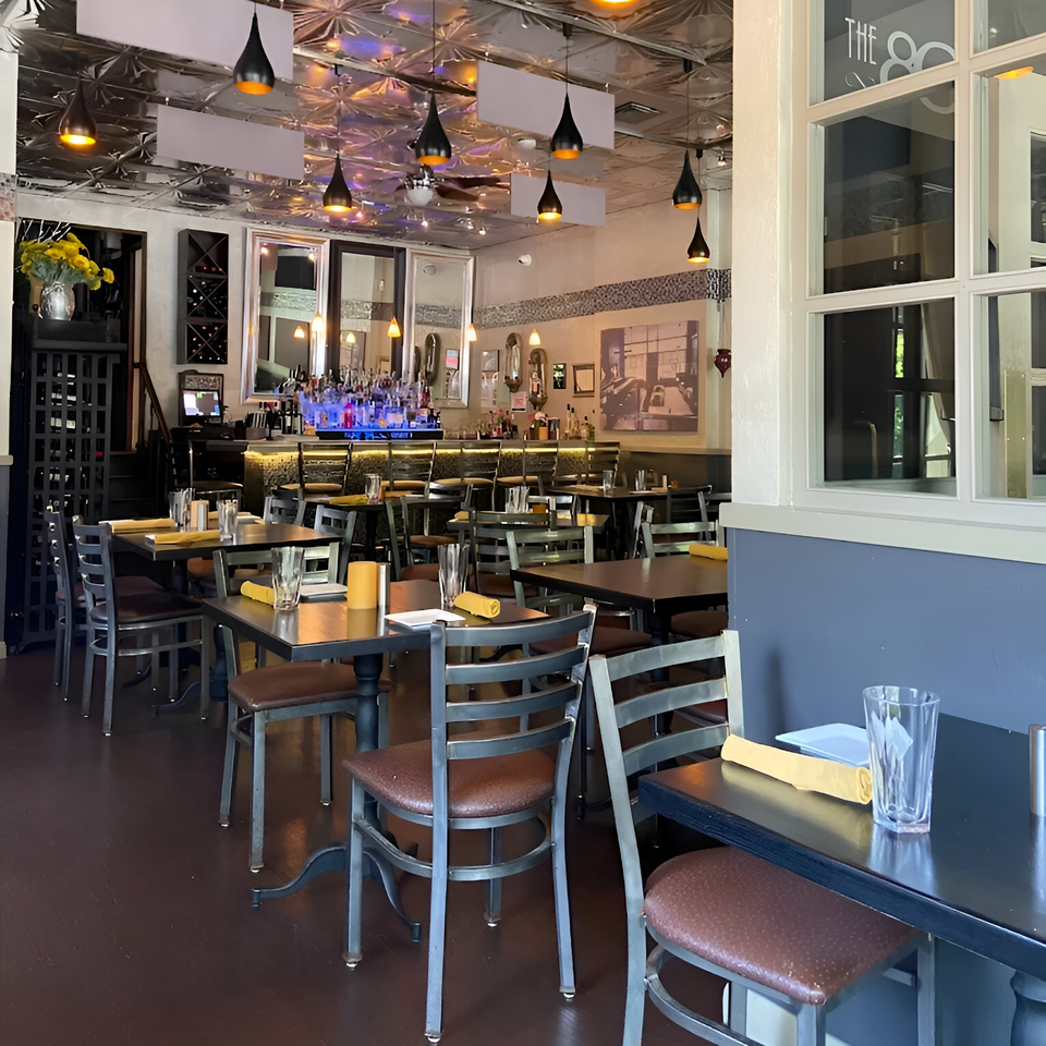 The 808 Bistro's dining room with tables, chairs, and a bar in the background.